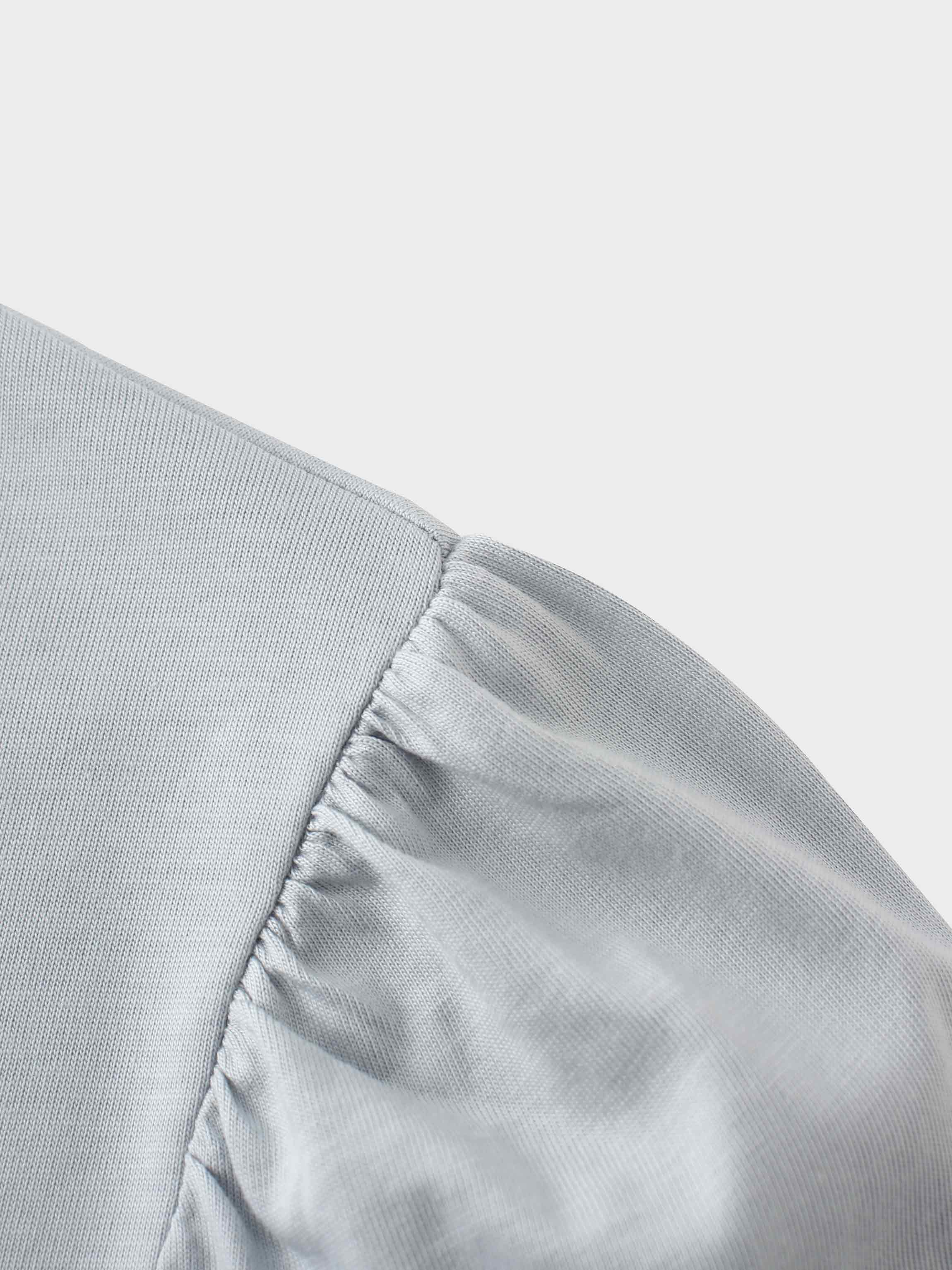 A close-up of the shoulder of the light gray shirt. The fabric at the top of the sleeve is gathered where it is sewn into the shoulder, creating a puff sleeve detail.