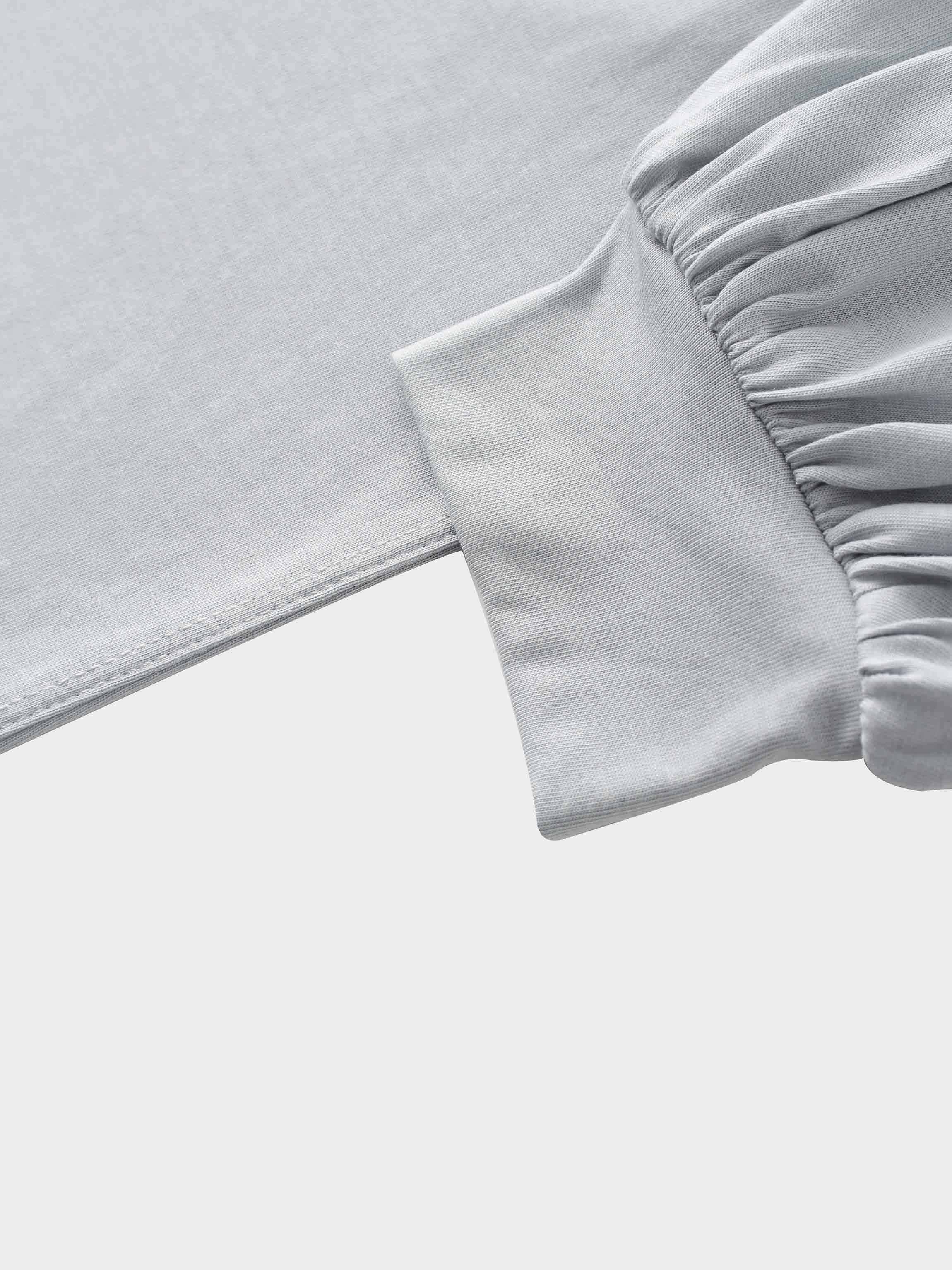 A close-up of the sleeve of the light gray garment, showing how the main fabric is gathered where it attaches to a wide, smooth cuff at the wrist.