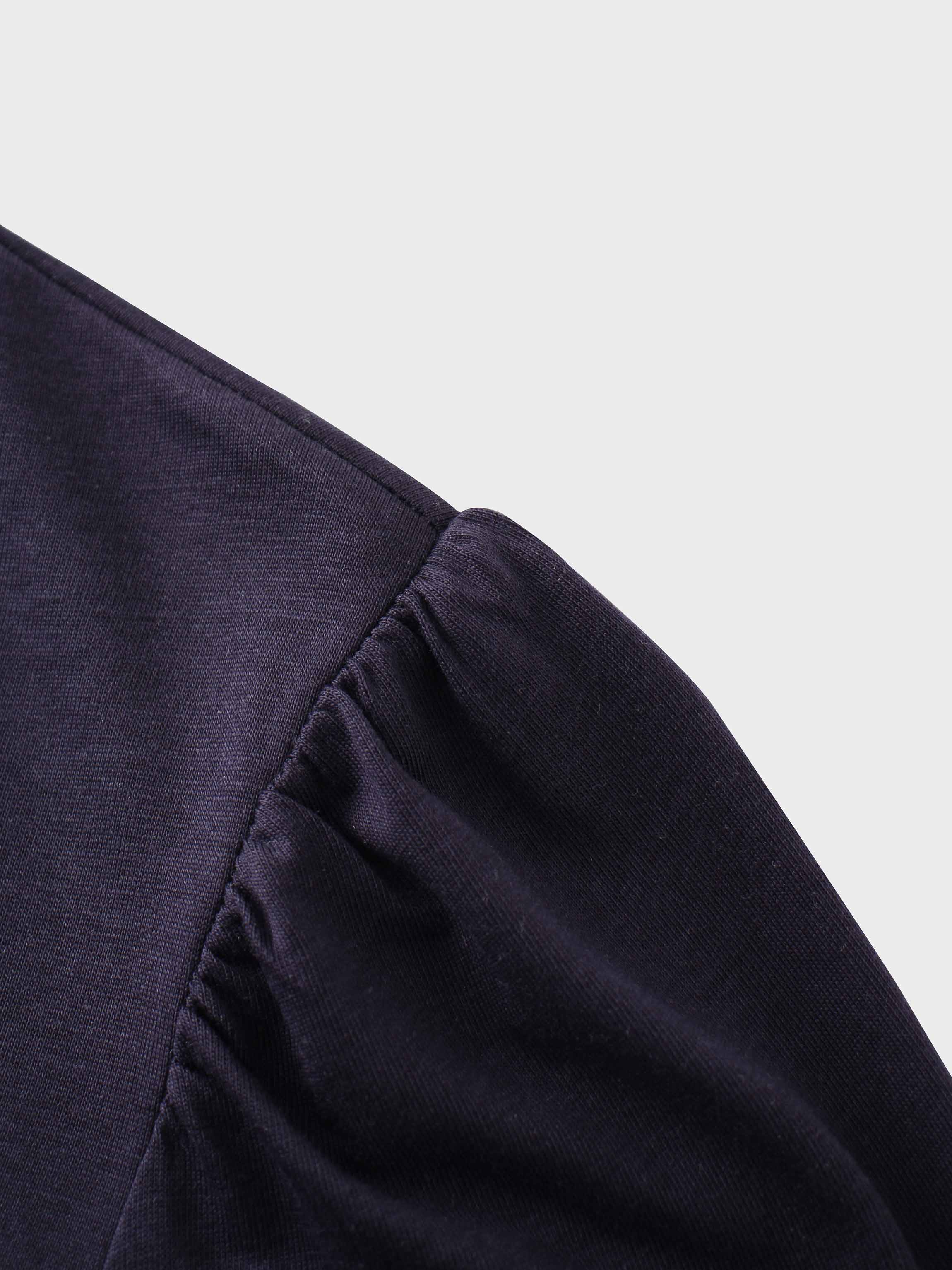 A close-up of the shoulder of the dark purple shirt. The fabric at the top of the sleeve is gathered where it is sewn into the shoulder, creating a puff sleeve detail.