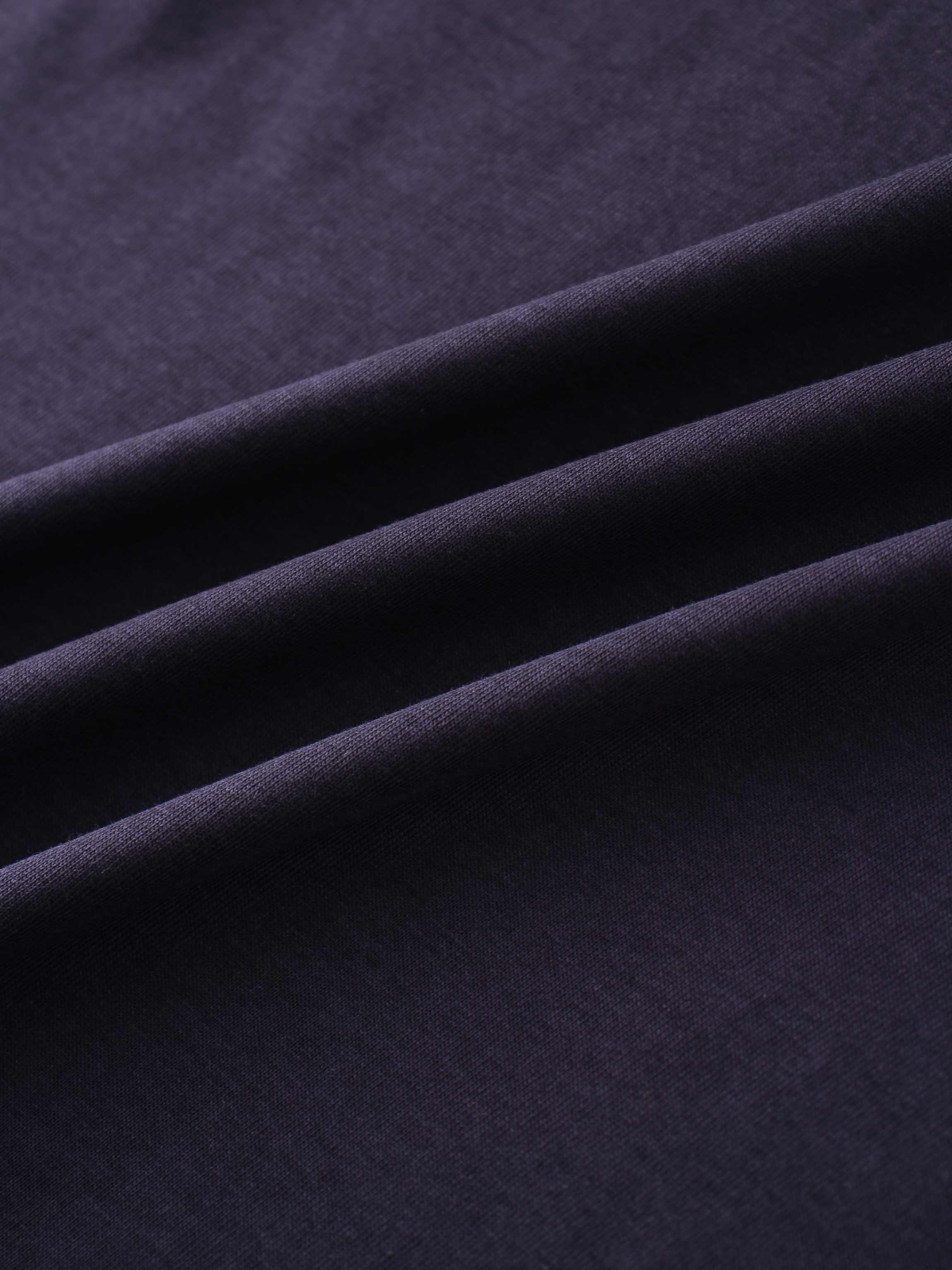 A close-up of a smooth fabric in a deep, dark purple color. The material is arranged in several soft, diagonal folds.