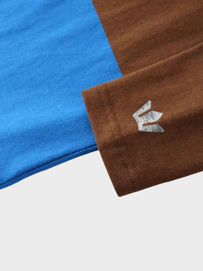 A sleeve of a blue and brown shirt with a silver crown-like logo.