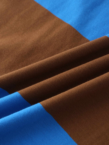 A close-up of a color-blocked fabric arranged in soft folds. The smooth material features wide panels of rich brown and vibrant blue.