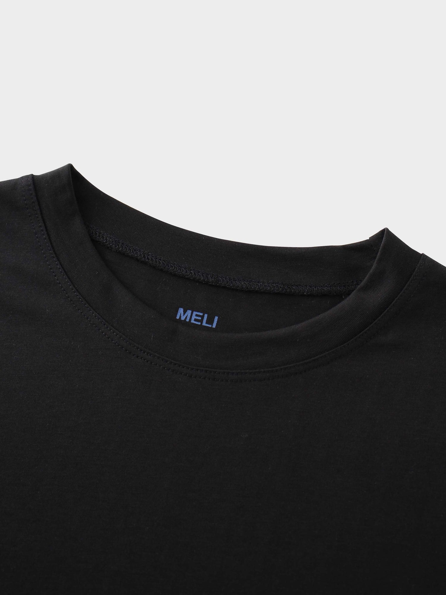 A close-up of the crewneck collar of the black t-shirt. On the inside, the brand name &quot;MELI&quot; is printed directly onto the fabric in blue.