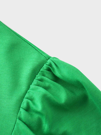 A close-up of the shoulder of the vibrant green shirt. The fabric at the top of the sleeve is gathered where it is sewn into the shoulder, creating a puff sleeve detail.