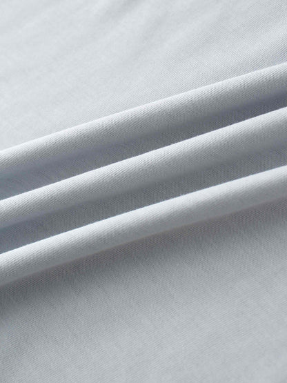 A close-up of the smooth, light gray fabric. The material is gathered into several soft, diagonal folds that catch the light.