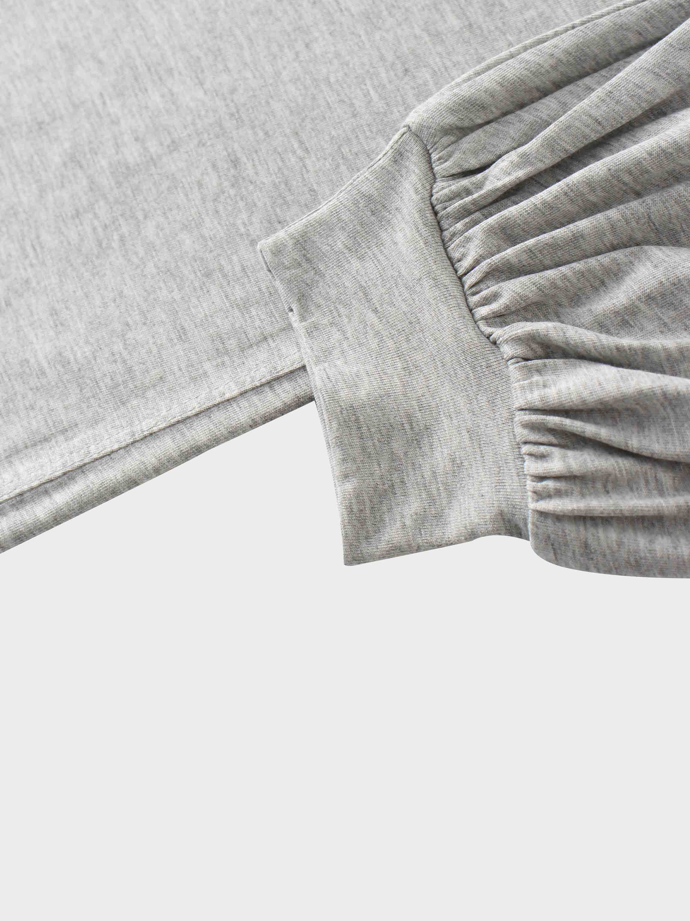 A close-up of the sleeve cuff on the heather gray garment. The main sleeve fabric is gathered where it attaches to a wide, smooth cuff band.
