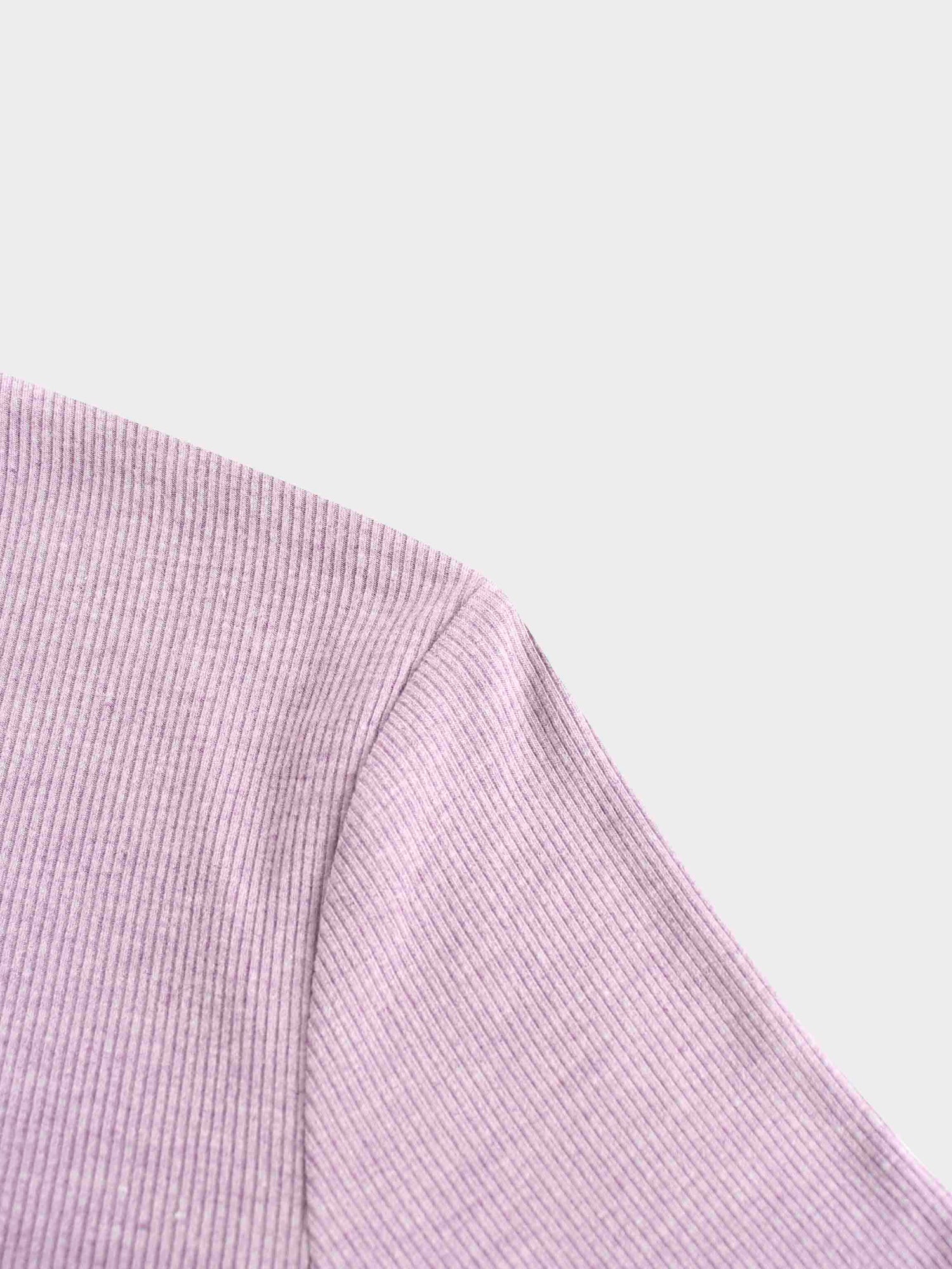 A close-up photo of the shoulder of the lavender-colored top. The image shows the seam where the sleeve is attached to the body of the ribbed garment.